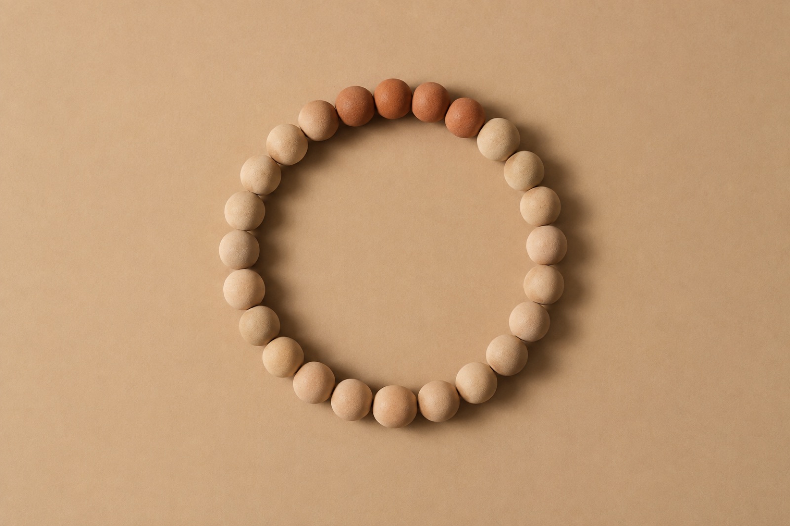 Mapuputlang butil na clay na nakaayos nang pabilog sa beige na background, at ang apat lang sa itaas ang mas matingkad na kahel