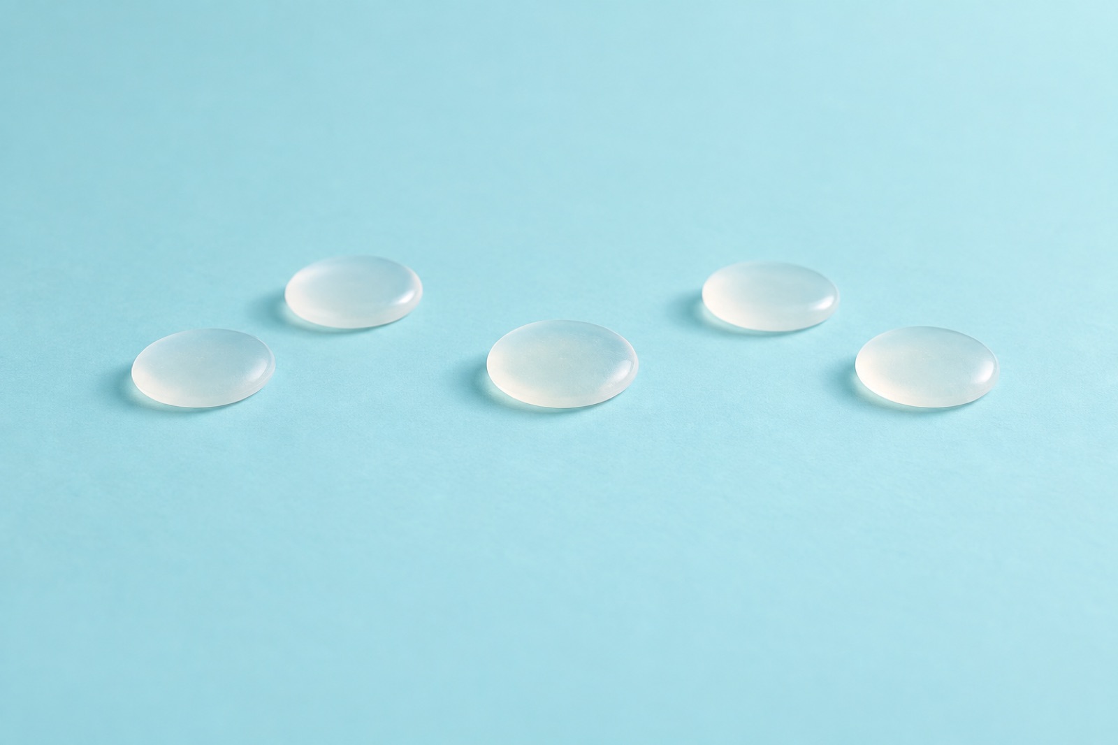 水色の背景の上に、半透明の丸いジェルのかけらが5つ、間をあけて置かれた様子